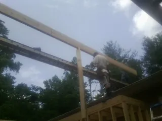 Carpenter setting a ridge beam over a new addition frame — Ice Dam Removal by Roofing Brothers in Gloverville