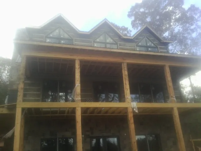 Dormers and porch framing on a large log home under construction — Roof Coating work by our crew in Gloverville