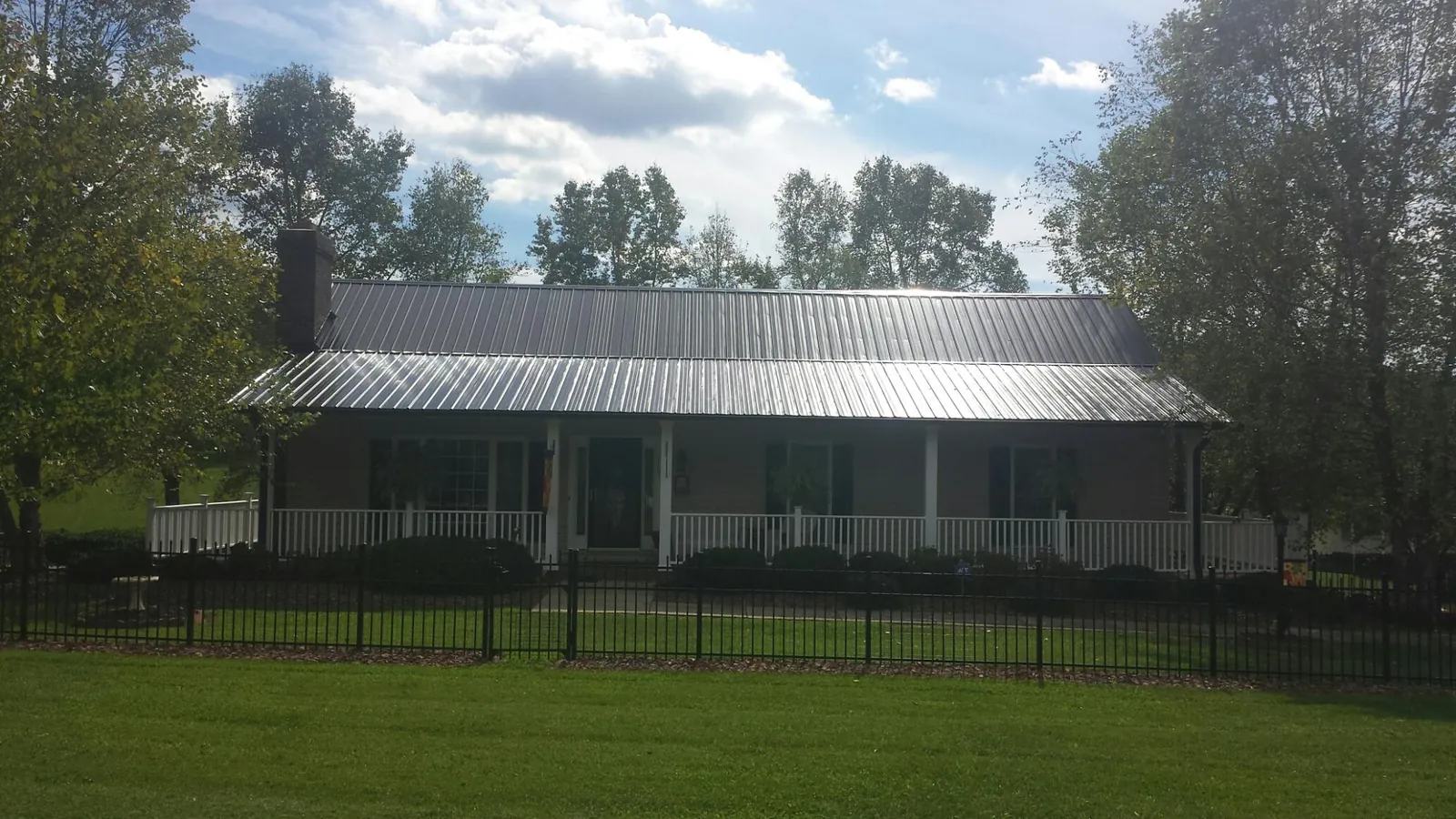 Gray metal roof on a brick ranch with a full width front porch — Gutter Guard Installation work by our crew in Gloverville
