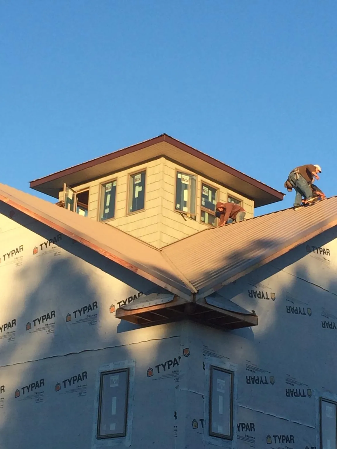 Roofers working around a rooftop cupola on a new metal roof at sunset — Roof Waterproofing in Gloverville by Roofing Brothers